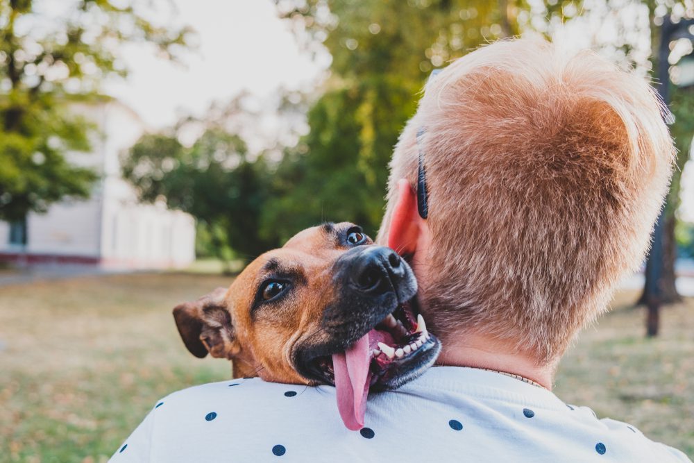 young man hugging dog outside